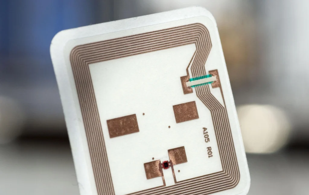 Close-up of a passive RFID tag showing the integrated microchip and copper antenna used for wireless identification, inventory tracking, and asset management.